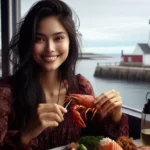 A delighted Indo-American woman enjoys fresh seafood at a waterfront restaurant in St. Andrews by-the-Sea, with the charming harbor and lighthouses in the background.